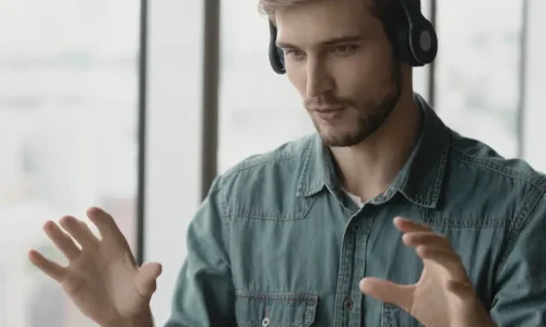 Online Business Coaching Session with Entrepreneur Using Virtual Meeting Tools Male entrepreneur receiving online business coaching during a virtual video session, wearing headphones and speaking confidently in a remote meeting setting